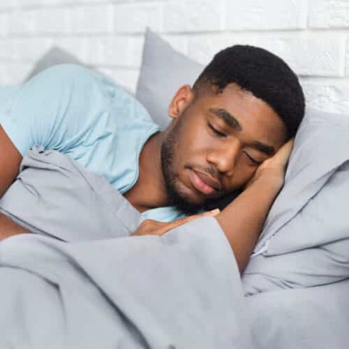 Young african-american man sleeping in bed at home Young african-american man sleeping adult sleep apnea treatment forest bedford lynchburg